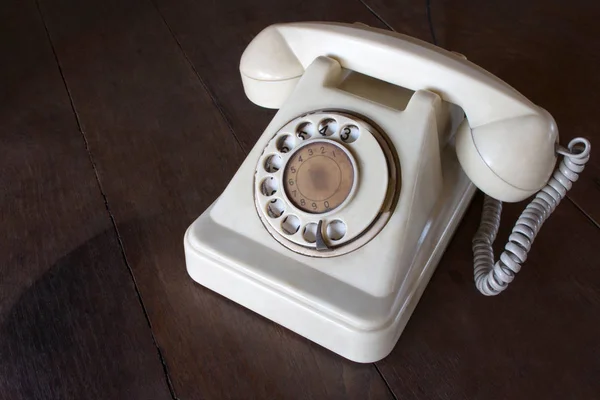 Régi fehér telefon por, kör dial pad és a karcolásoktól, fából készült retro asztal. — Stock Fotó