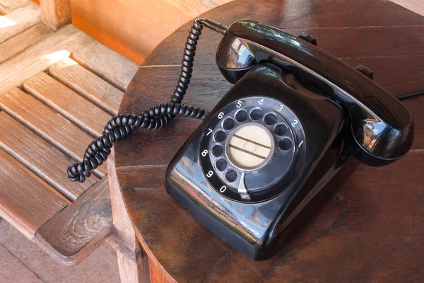 Régi fekete telefon por, kör dial pad és a karcolásoktól, fából készült retro asztal. — Stock Fotó