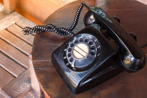 Régi fekete telefon por, kör dial pad és a karcolásoktól, fából készült retro asztal. — Stock Fotó