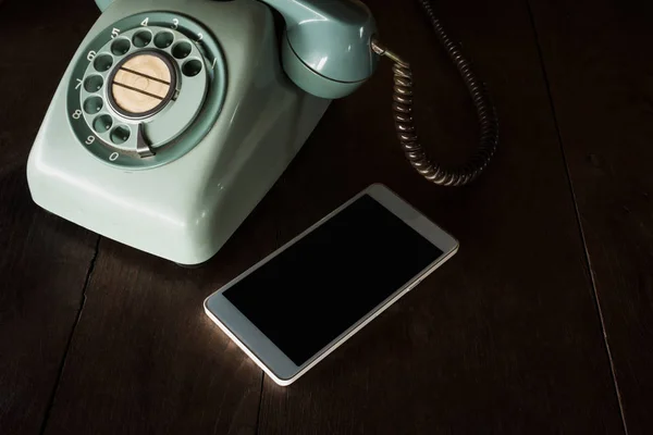 A telefon két különböző technológia. Modern mozgatható telefon és régi vintage klasszikus telefon, fából készült tábla, hogy összehasonlítsák és kontraszt. Régi telefon és új telefon fogalom. — Stock Fotó