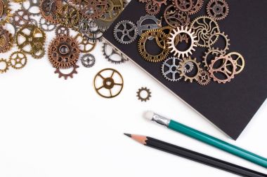 İş araçları ve iş başarı kavramı. Defter ve kalem ile beyaz bir arka plan üzerinde izole paslı metal Dişliler.