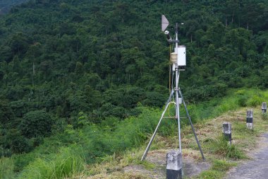 Anten meteorolojik hava istasyon ile meteoroloji sensörler, soluk bulutlu bulutlu gökyüzü ve orman içinde geçmiş. Hava durumu istasyonunun arka planı için.