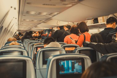 Los Angeles, Usa 12, 2017: İnsanlar karaya çıkmadan önce bir uçak kulübesinde ayakta ve oturuyorlar. Los Angeles, Kaliforniya 'da inecek yolcularla dolu bir uçağın içinde..