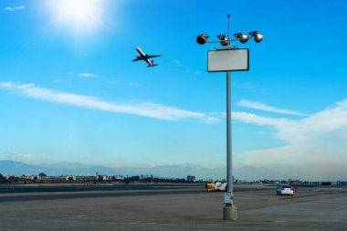 Uçak, lamba direği olan bir havaalanı. Arka planda mesaj, kamyon, araba ve pist var. Uçak pisti ve boş afişi olan açık hava parkı.