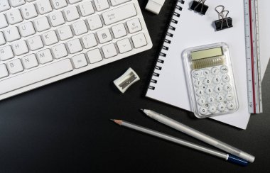 Bilgisayar klavyesi, iş gereçleri ve kopyalama alanı olan siyah beyaz ofis masası. Çalışma masası ile üst görünüm ve metin için yer kopyala.