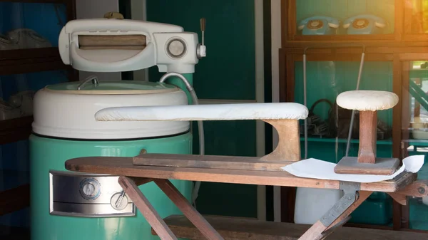 Eski çamaşır makineleri, elektrik kurutma makinesi, çamaşırhanede çamaşır ütüleme tahtası ve kuru temizleme atölyesi. Antika çamaşırhane konsepti.