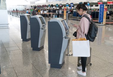 Hong Kong, Çin - 19 Mart 2018: Asyalı kadın, Hong Kong Uluslararası Havalimanı Terminal 1 'de kendi kendine kontrol makineleri kullanarak giriş yapıyor..