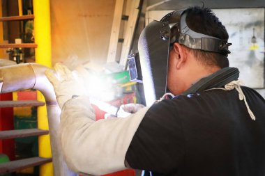 Fabrikadaki çelik kaynakçılarının işçi işçilerini kapatıyoruz. Metal kaynaklama ve ışık saçan koruyucu maskeli bir işçi.