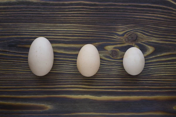 लकड़ी की पृष्ठभूमि पर पड़े तीन अलग-अलग अंडे यो दिखा सकते हैं — स्टॉक फ़ोटो, इमेज