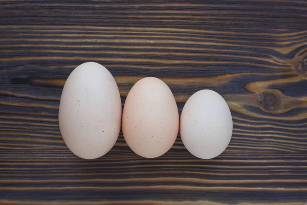 Three different eggs laying on the wooden background can show yo — Stock Photo, Image