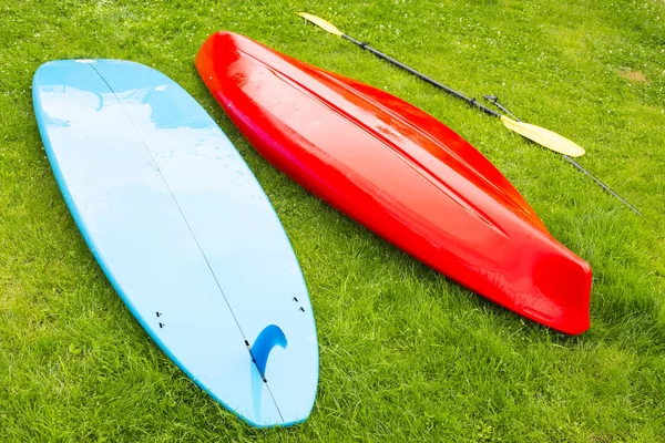 Windsurf barco e caiaque com remo coloca no gramado verde — Fotografia de Stock