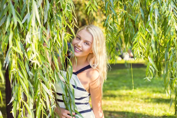 Krásný veselý mladá žena stojící poblíž stromu ve městě — Stock fotografie