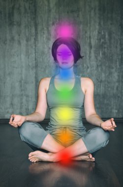 Çakralarla meditasyon yapan bir kadın. Güzel genç bir kadın, vücuttaki çakraların aktifleştirilmesiyle lotus duruşu içinde yoga meditasyonu yapıyor.
