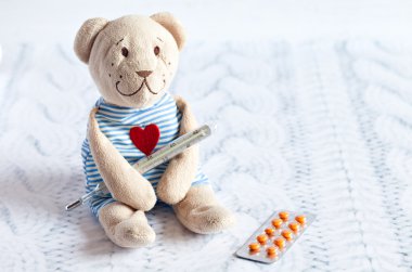 Çocuk yumuşak oyuncak ayıcık hapları ile Merkür cam termometre sıcaklığı alır. Childs'ın hastalığı.