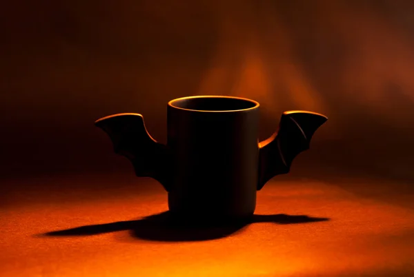 Kopp kaffe som bat för Halloween på svart bakgrund. Rött ljus och skugga. Leksak. konceptet — Stockfoto