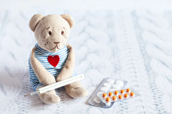 Orsacchiotto peluche per bambini con pillole prende la temperatura di un termometro in vetro di mercurio. malattia dei bambini . — Foto Stock