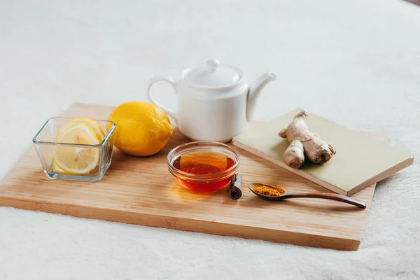 Té de hierbas con flores de manzanilla, cúrcuma y miel en una tabla de madera. Tratamiento de la bebida caliente con jengibre. Tratamiento de remedios caseros en la cama . — Foto de Stock