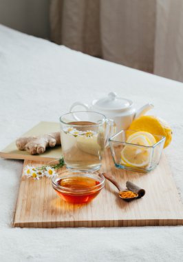 Bitkisel çay papatya çiçeği, zerdeçal ve ballı bir ahşap tahta üzerinde. Zencefil ile sıcak içecek tedavisinde. Halk ilaçları yatakta tedavi.