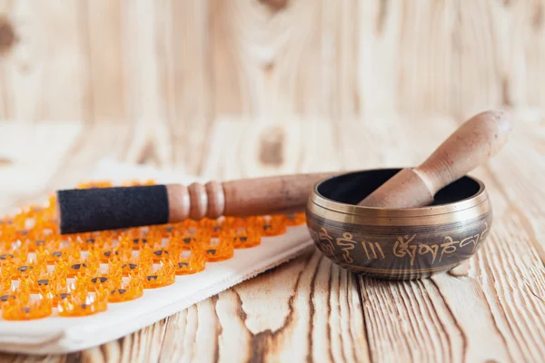 Singing bowl on wooden background. Burning candles and oil for aromatherapy and massage. — Stock Photo, Image
