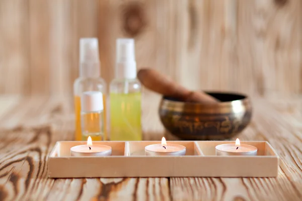 Singing bowl on wooden background. Burning candles and oil for aromatherapy and massage. — Stockfoto
