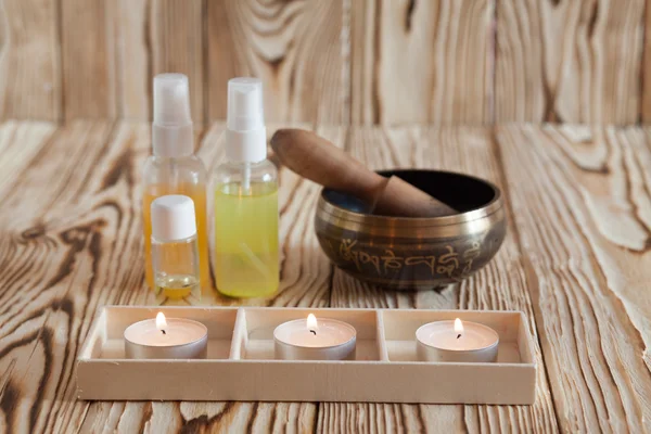 Singing bowl on wooden background. Burning candles and oil for aromatherapy  massage. — Stockfoto
