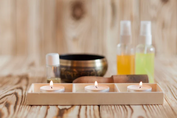 Singing bowl on wooden background. Burning candles and oil for aromatherapy  massage. — Stockfoto