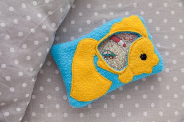 Çocuk yumuşak oyuncak goldfish motor gelişim için renkli Polar yapılmıştır. Plastik boncuk ve figürler üzerinde beyaz bezelye bir arka plan gri kumaş çanta dolu. el yapımı oyuncaklar.