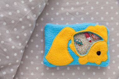 Çocuk yumuşak oyuncak goldfish motor gelişim için renkli Polar yapılmıştır. Plastik boncuk ve figürler üzerinde beyaz bezelye bir arka plan gri kumaş çanta dolu. el yapımı oyuncaklar.