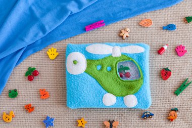 Motor gelişim için renkli yün çocuk yumuşak oyuncak mavi helikopter. Plastik boncuk ve figürler arka planda dağınık oyuncak ve mavi kumaş çanta Polar dolu. el yapımı oyuncaklar.