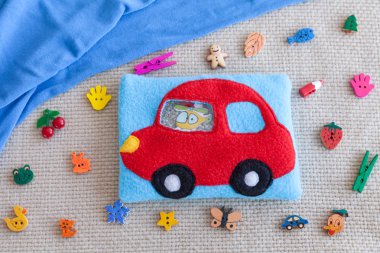 Renkli yün, çocuk yumuşak oyuncak kırmızı makine motor gelişim için. Plastik boncuk ve figürler arka planda dağınık oyuncak ve mavi kumaş çanta Polar dolu. el yapımı oyuncaklar.