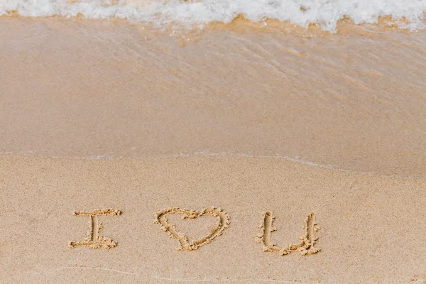 Eu te amo - a inscrição na praia de areia com uma onda suave . — Fotografia de Stock