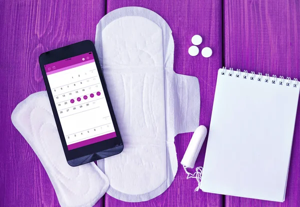 Menstruatie dingen en agenda op smartphone — Stockfoto