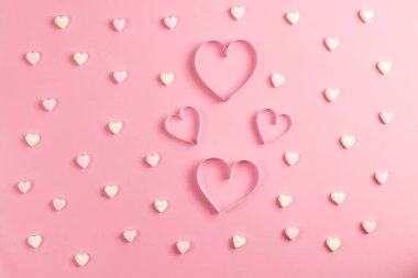 Sevgililer Günü için 14 Şubat 'ta kompozisyon. Narin pembe bir arka plan ve kağıttan kesilmiş bir kalp. Kalp şeklinde sarı ve pembe şekerlemeler. Tebrik kartı. Düz konum, üst görünüm, kopyalama alanı