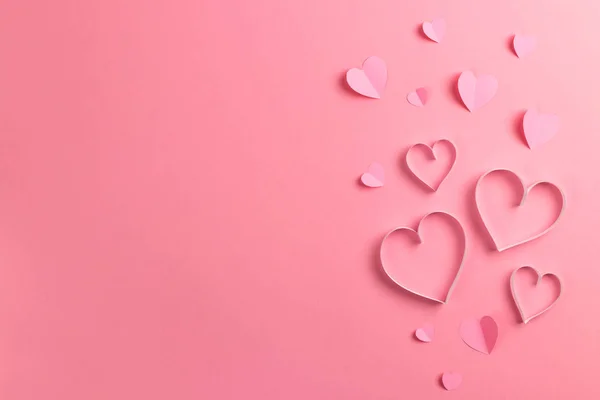 Komposition zum Valentinstag am 14. Februar. Zarter rosa Hintergrund und rosa Herzen aus Papier ausgeschnitten. Grußkarte vorhanden. Flache Lage, Draufsicht, Kopierraum. lizenzfreie Stockfotos