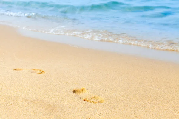 Pegadas na areia numa praia junto ao mar. Conceito de férias de verão. ondas azuis no fundo. Relaxe na praia de areia. Espaço de cópia . — Fotografia de Stock