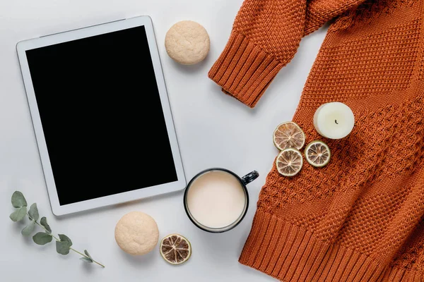 Sonbahar kompozisyonu. Turuncu süveter ve beyaz bir masada bir fincan kakao ile dijital tablet. Yaşam tarzı, hala yaşam konsepti. Düz yatış, üst görünüm.