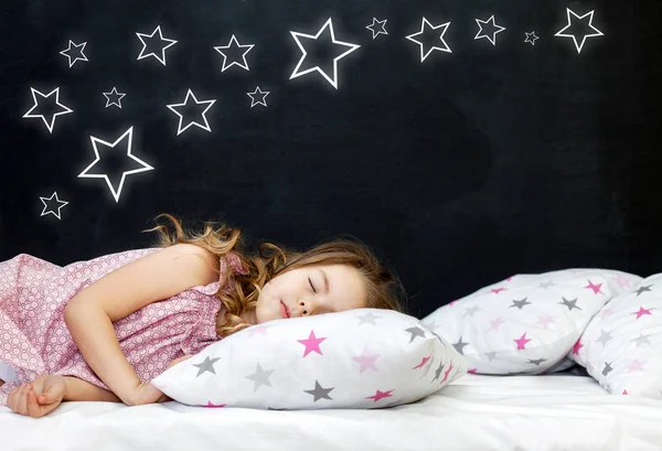 Charmante petite fille d'âge préscolaire dort au lit sur un oreiller étoilé. Il est temps de dormir. Contexte abstrait sur l'espace et les rêves d'un enfant. Un voyage dans un rêve. Bonne enfance Images De Stock Libres De Droits