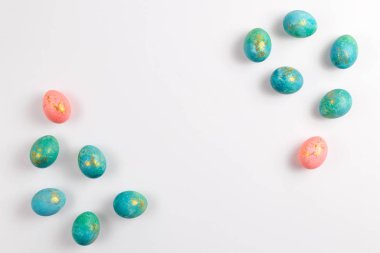 Mutlu Paskalyalar. Beyaz zemin üzerinde altın paskalya yumurtaları olan turkuazın şık minimalist kompozisyonu. Düz konum, üst görünüm, kopyalama alanı.