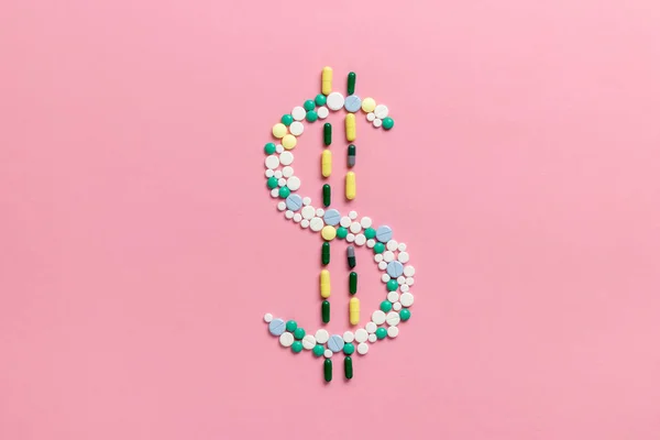 Composition of pills and capsules on a pink background in the form of a dollar sign. The concept of the cost of drugs and drug trafficking. Copy space. View from above. Flat lay. — Stock Photo, Image