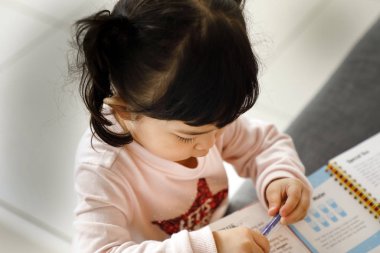 Kanepede oturan kız çocuğu yazarlık eğitimi alıyor.