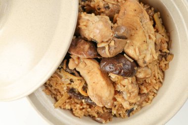 Beyaz arka planda killi seramik kasede mantarlı tavuk pilavı.