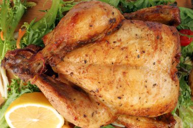 Ahşap kesim tahtasında fırında patates, sebze, limon salatası ve ızgara tavuk kümes hayvanı.