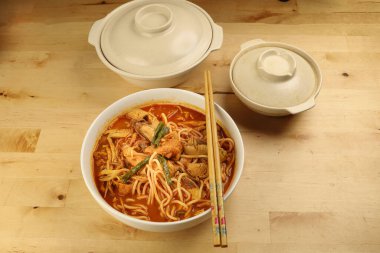 Ahşap zemin üzerinde kızarmış tavuk dilimlenmiş Malezya körili sarı eriştesi.