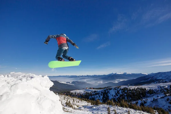 青空背景 Dragobrat スキー リゾート山中のスノーボーダーをジャンプ — ストック写真