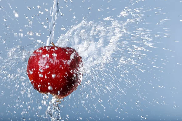 Red apple in water drops on blue background — Stock Photo, Image