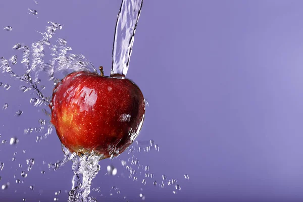 Red apple in water drops on purple background — Stock Photo, Image