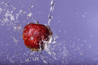 Mor arka plan üzerinde kırmızı elma suyu damla