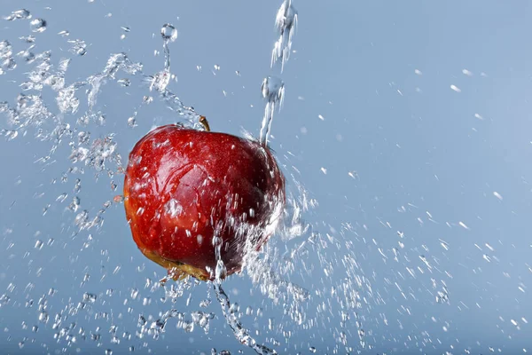 Red apple in water drops on blue background — Stock Photo, Image