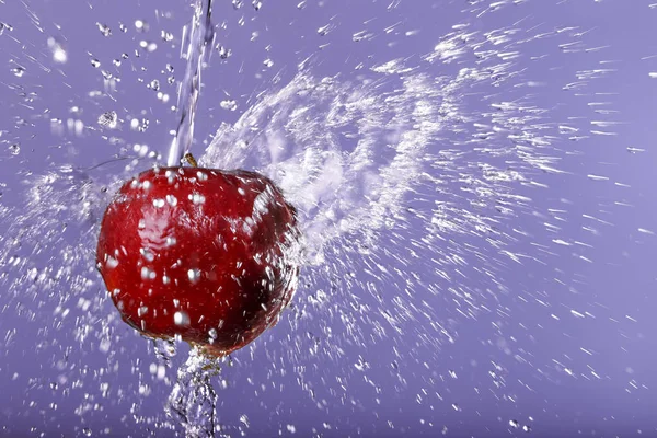 Red apple in water drops on purple background — Stock Photo, Image