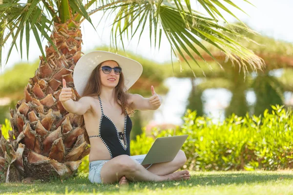 Woman working on laptop on the vacation. Girl with laptop under